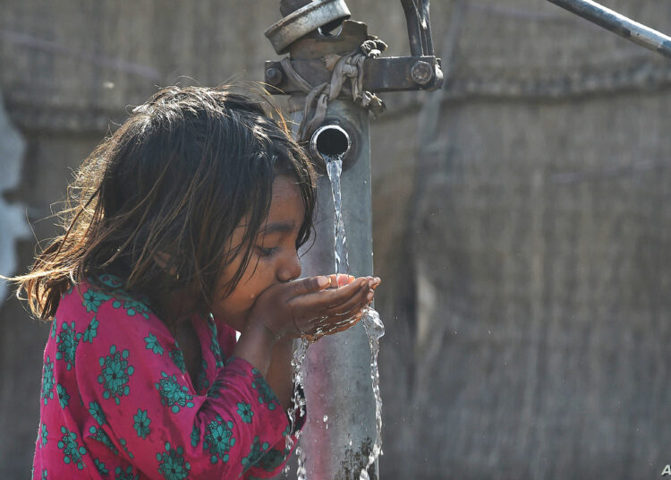 A Pakistani girl drinks water from a hand water pump in Lahore on March 22, 2019, on World Water Day. - Each year on March 22, World Water Day is observed around the world, focusing on the importance of fresh water and advocating for sustainable management of water resources. (Photo by ARIF ALI / AFP)